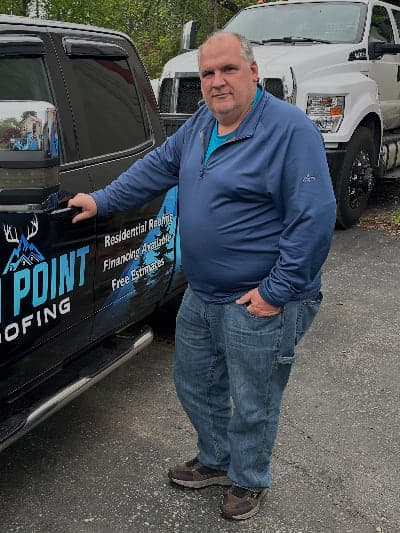 Mike Mesaris, production manager at Ten Point Roofing, beside a company truck